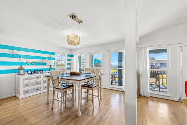 dining area with a textured ceiling, vaulted ceiling, a healthy amount of sunlight, and light wood-type flooring