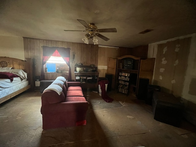 interior space featuring ceiling fan, concrete flooring, and wood walls