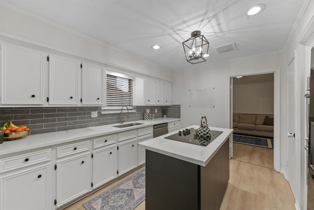 kitchen featuring black electric cooktop, sink, a kitchen island, and white cabinets