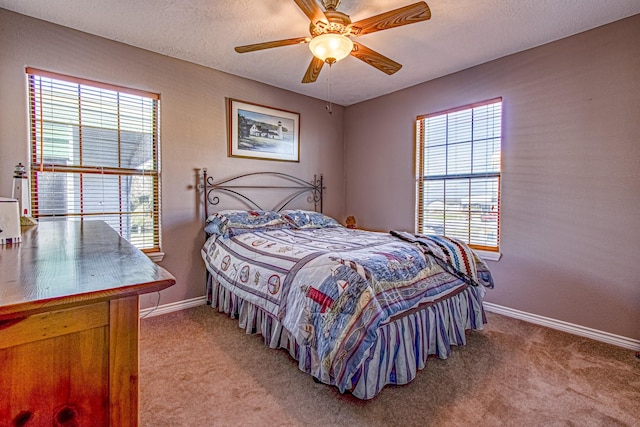 bedroom with ceiling fan, light colored carpet, multiple windows, and a textured ceiling