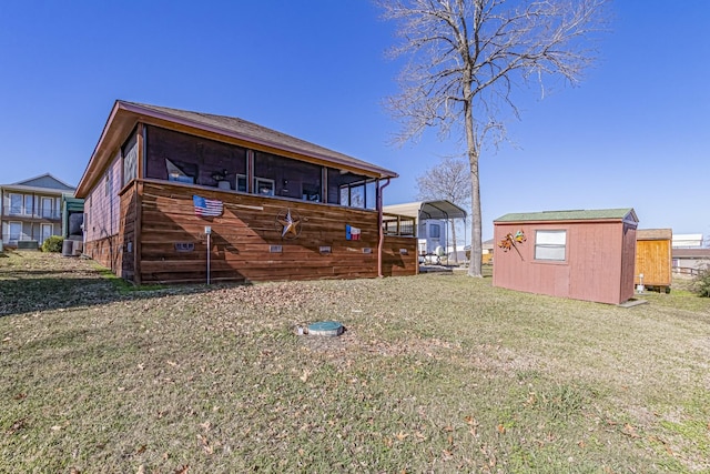 back of house featuring a carport, a storage shed, a lawn, and central AC