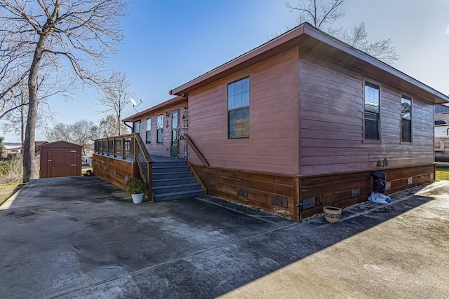 view of side of home featuring a wooden deck and a storage shed