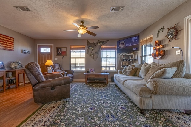 living room with ceiling fan, wood-type flooring, and a textured ceiling