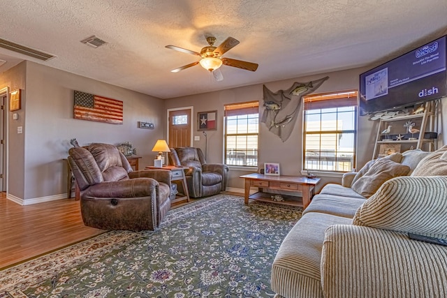 living room with ceiling fan, wood-type flooring, and a textured ceiling