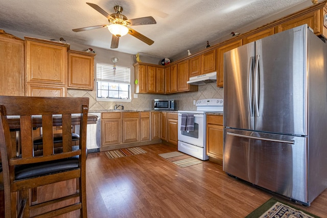 kitchen with a textured ceiling, appliances with stainless steel finishes, decorative backsplash, dark hardwood / wood-style floors, and ceiling fan