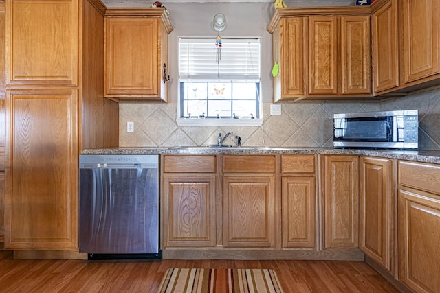 kitchen with tasteful backsplash, appliances with stainless steel finishes, and light hardwood / wood-style floors