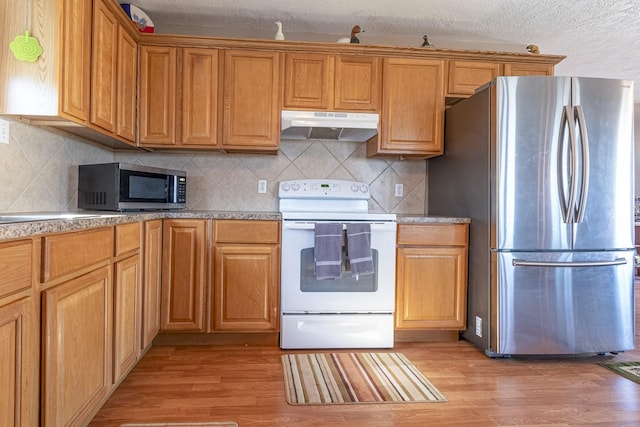 kitchen featuring a textured ceiling, appliances with stainless steel finishes, backsplash, and light hardwood / wood-style flooring