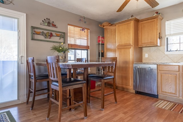 kitchen featuring ceiling fan, decorative backsplash, light wood-type flooring, a textured ceiling, and stainless steel dishwasher