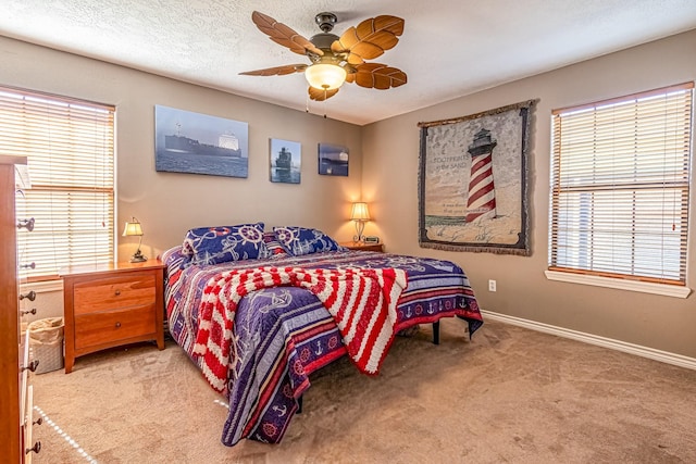 carpeted bedroom featuring ceiling fan, multiple windows, and a textured ceiling