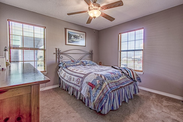 carpeted bedroom with a textured ceiling, ceiling fan, and multiple windows