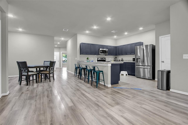 kitchen featuring light wood-type flooring, appliances with stainless steel finishes, a breakfast bar, and a center island