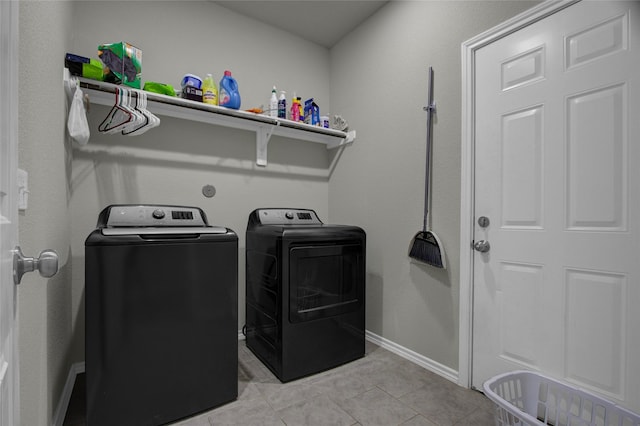 clothes washing area with washing machine and dryer and light tile patterned floors