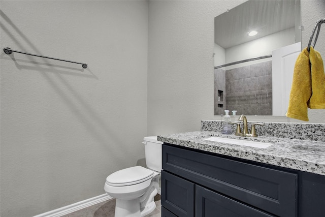 bathroom featuring toilet, tiled shower, and vanity