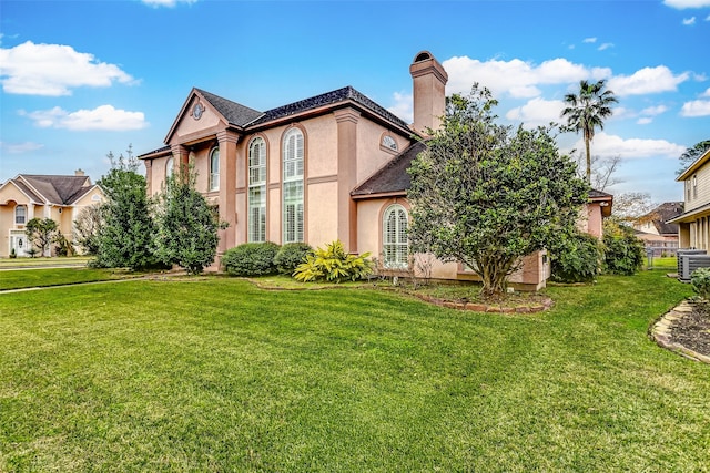 view of front of house with a chimney, central AC unit, a front lawn, and stucco siding