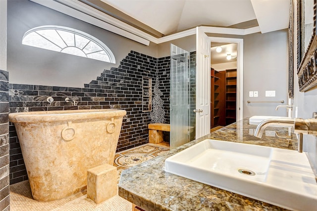 bathroom with tile walls, lofted ceiling, wainscoting, a sink, and tile patterned flooring