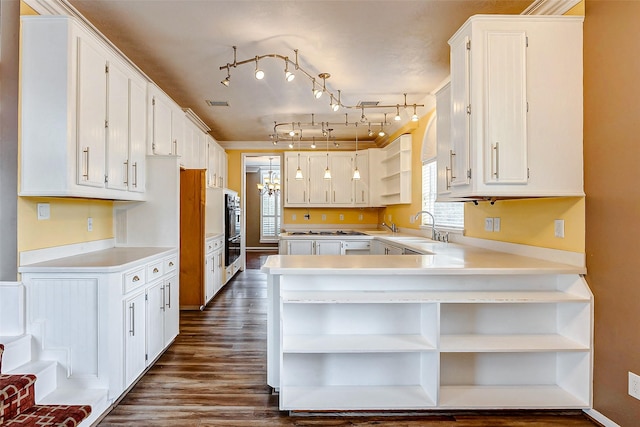 kitchen with white cabinetry, kitchen peninsula, double wall oven, dark hardwood / wood-style floors, and sink