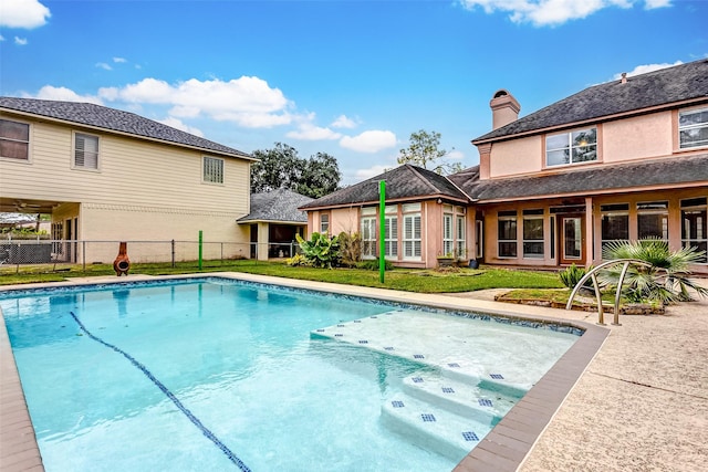 view of swimming pool featuring a lawn, fence, and a fenced in pool