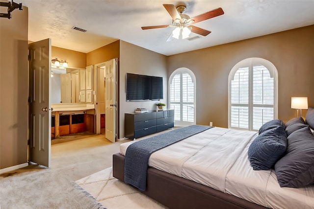 bedroom featuring ceiling fan, light carpet, and connected bathroom