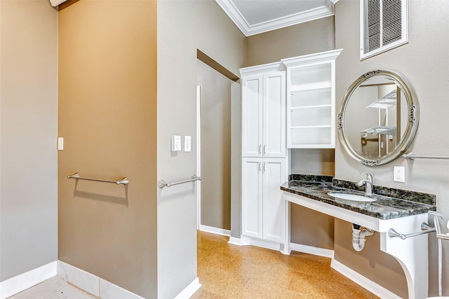 bathroom featuring a sink, visible vents, baseboards, and crown molding