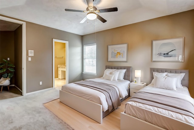 bedroom with ceiling fan, ensuite bath, and light colored carpet