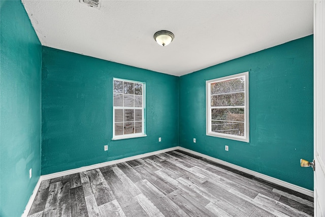 unfurnished room with hardwood / wood-style flooring and a textured ceiling