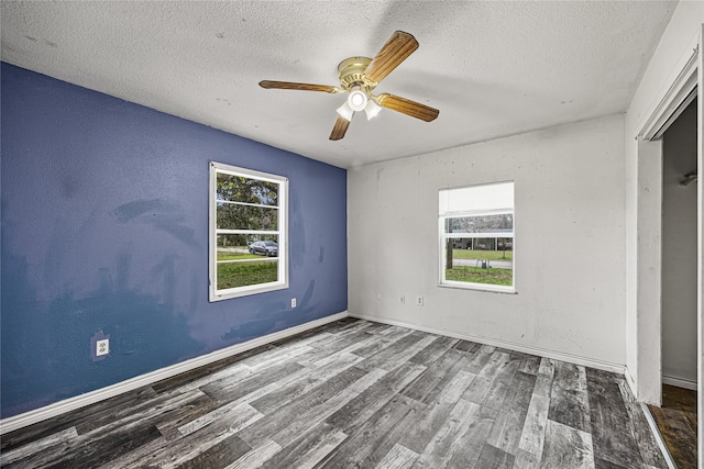 unfurnished bedroom with dark wood-type flooring, ceiling fan, a textured ceiling, and multiple windows