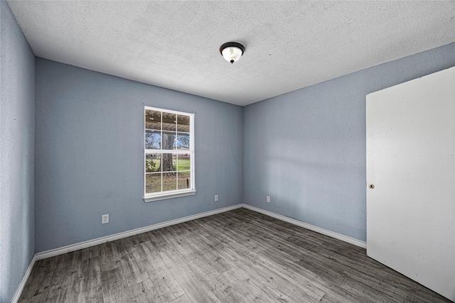 spare room featuring wood-type flooring and a textured ceiling