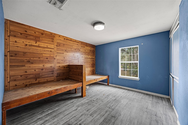 unfurnished bedroom featuring wood-type flooring and wooden walls