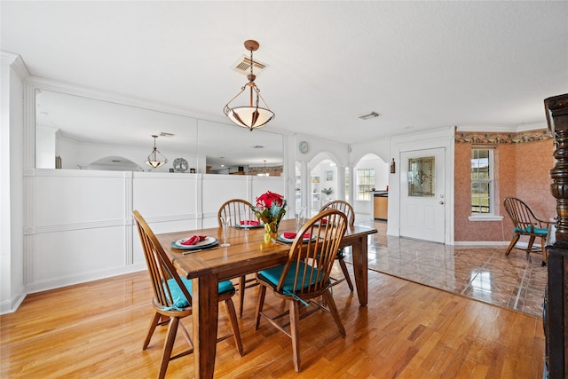 dining space with ornamental molding and light hardwood / wood-style floors