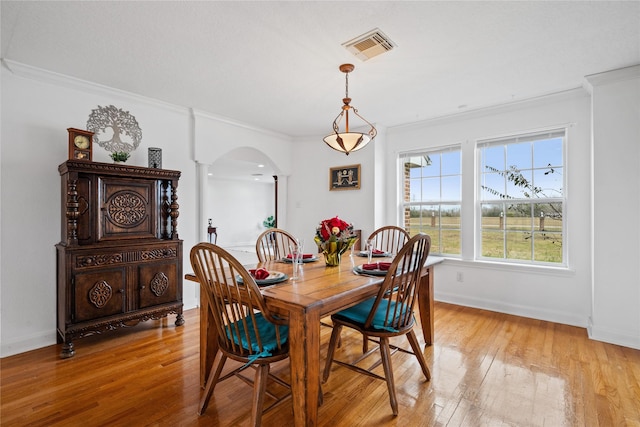 dining area with light hardwood / wood-style flooring, crown molding, and ornate columns