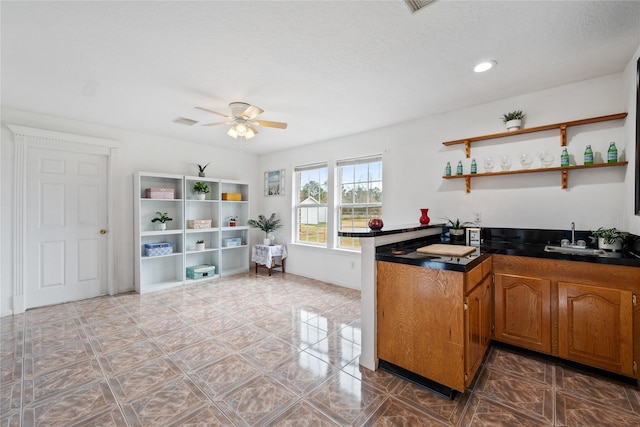 kitchen with a textured ceiling, ceiling fan, and sink