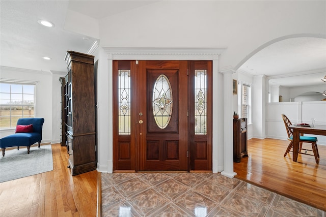 foyer entrance with hardwood / wood-style flooring, ornamental molding, and ornate columns