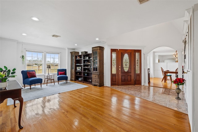 foyer with crown molding and light hardwood / wood-style floors