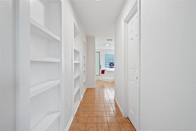 hallway with light tile patterned flooring and built in shelves