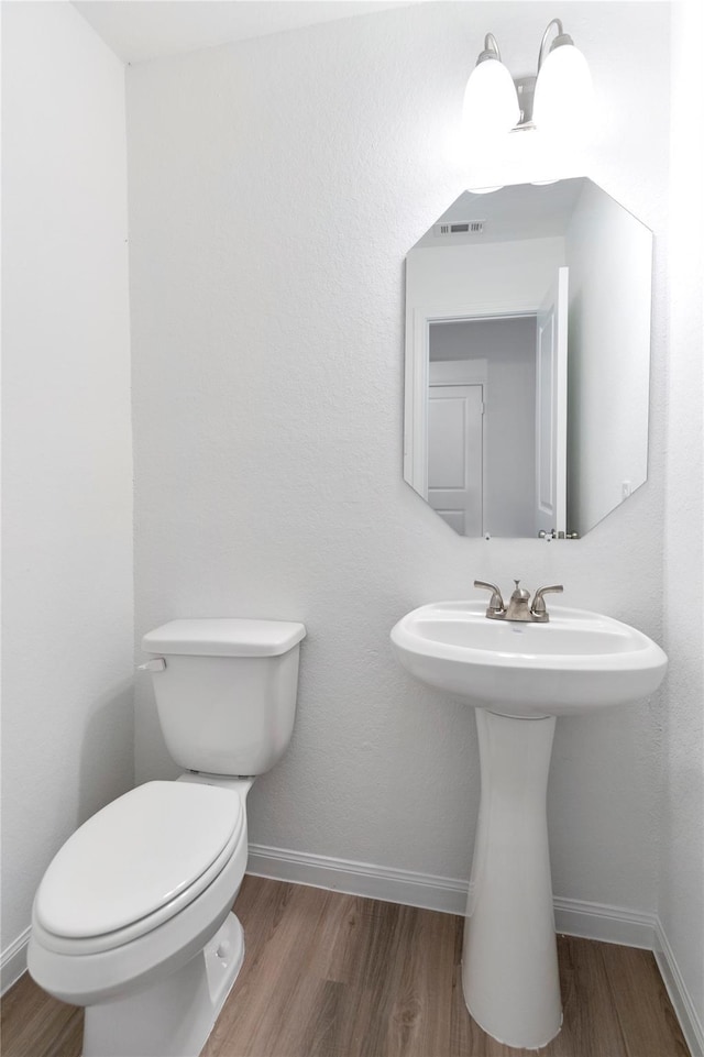 bathroom with toilet, hardwood / wood-style floors, and sink