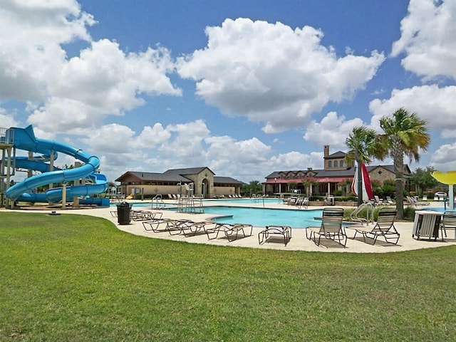 view of swimming pool featuring a water slide and a lawn