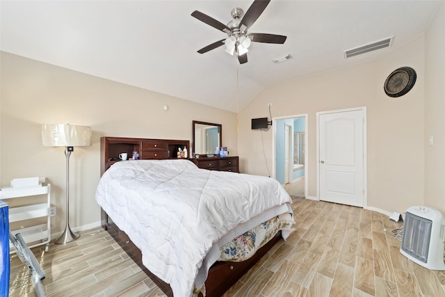 bedroom with connected bathroom, heating unit, vaulted ceiling, ceiling fan, and light hardwood / wood-style floors