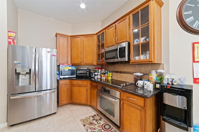 kitchen with stainless steel appliances, light tile patterned floors, decorative backsplash, and dark stone counters