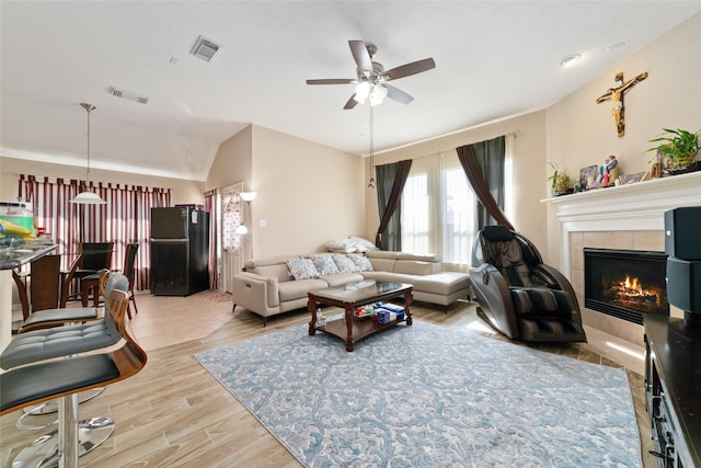 living room featuring lofted ceiling, a fireplace, and ceiling fan