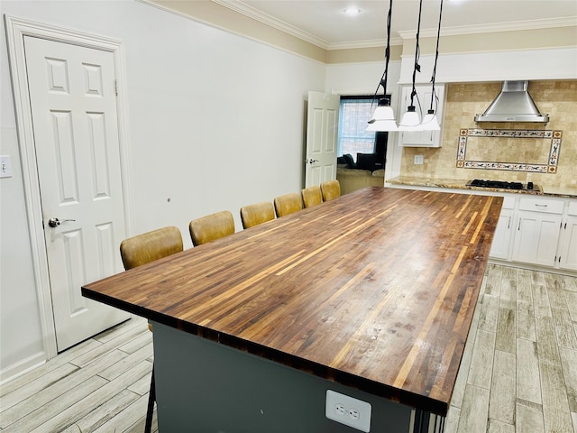 kitchen with hanging light fixtures, white cabinets, butcher block counters, and a breakfast bar area