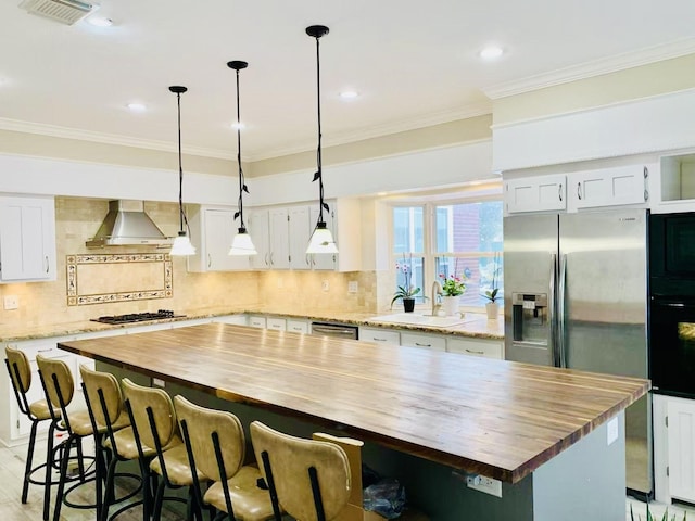 kitchen with white cabinetry, a center island, wooden counters, and wall chimney exhaust hood