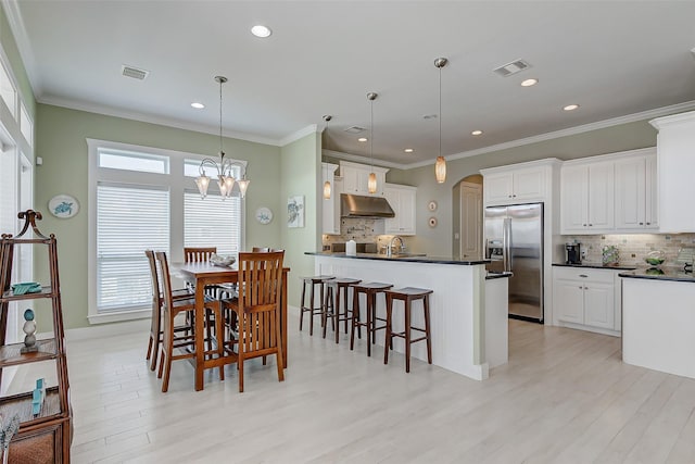 dining space with sink, crown molding, a chandelier, and light hardwood / wood-style flooring