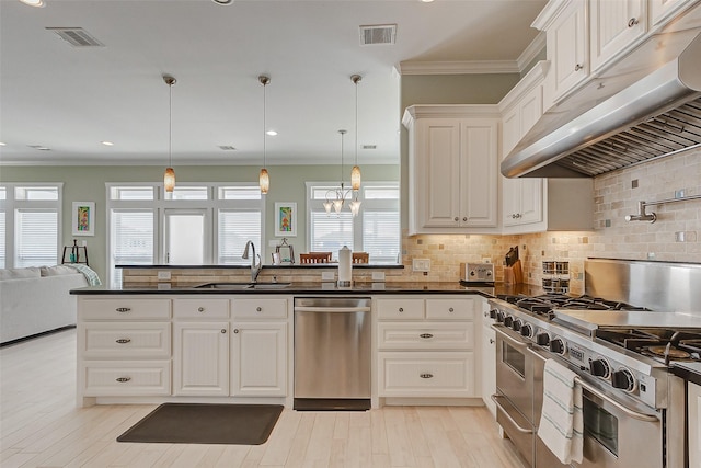 kitchen with decorative light fixtures, sink, crown molding, stainless steel appliances, and white cabinets