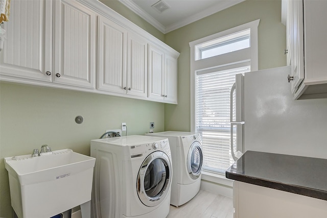 laundry area featuring cabinets, sink, washer and dryer, and ornamental molding