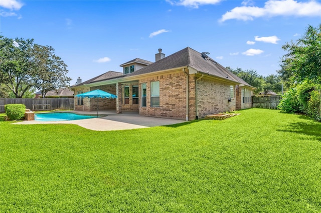 rear view of property with a fenced in pool, a lawn, and a patio