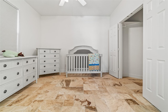 unfurnished bedroom with a nursery area and ceiling fan