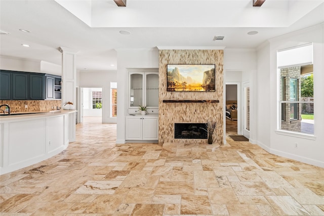 unfurnished living room with ornamental molding and a large fireplace