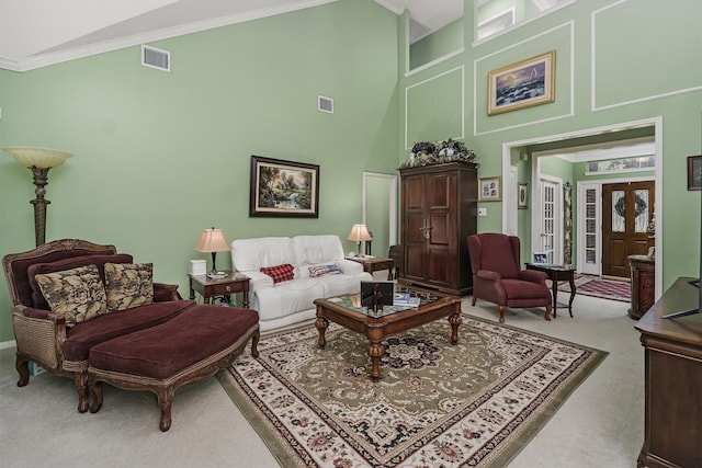 living area with crown molding, a towering ceiling, french doors, and carpet