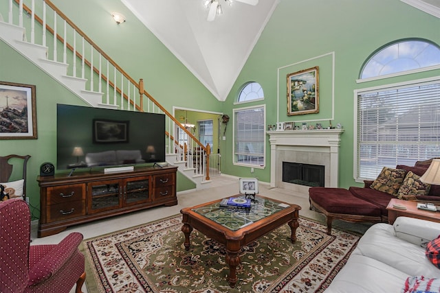 living room with a tile fireplace, ornamental molding, a chandelier, and high vaulted ceiling