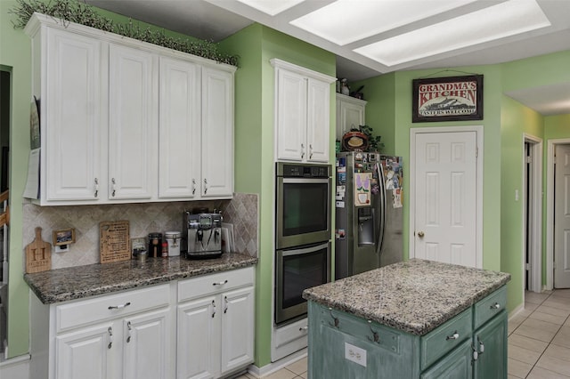 kitchen with white cabinetry, light tile patterned floors, a kitchen island, stainless steel appliances, and decorative backsplash